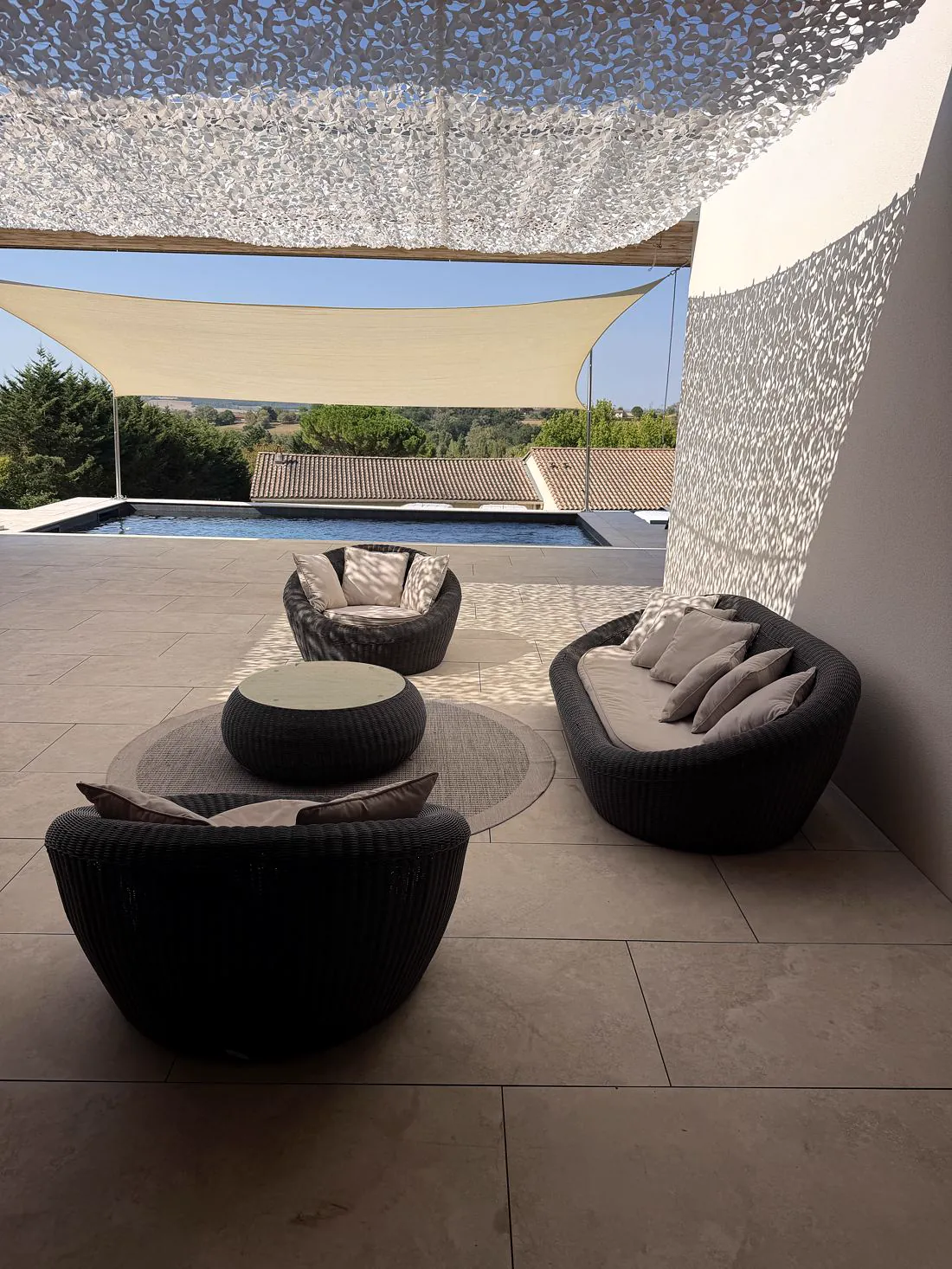 Salon de terrasse ombragé sous voiles d'ombrage, vue piscine et campagne