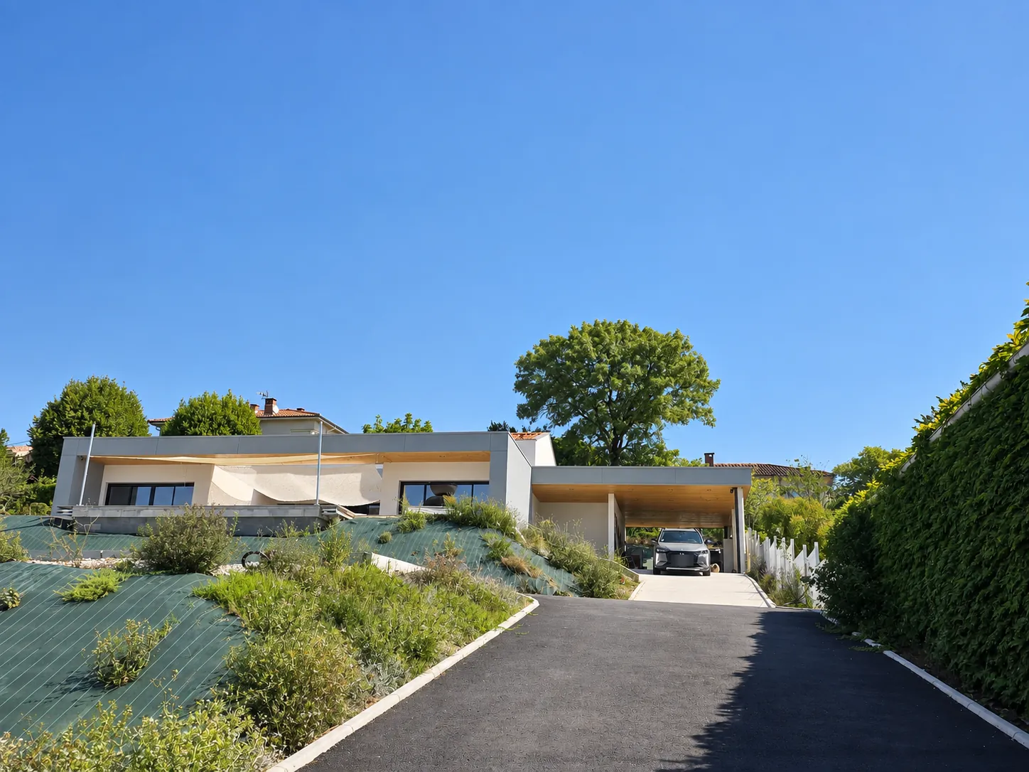 L'Escapade Caramanaise vue depuis l'allée : la maison contemporaine et son parking couvert